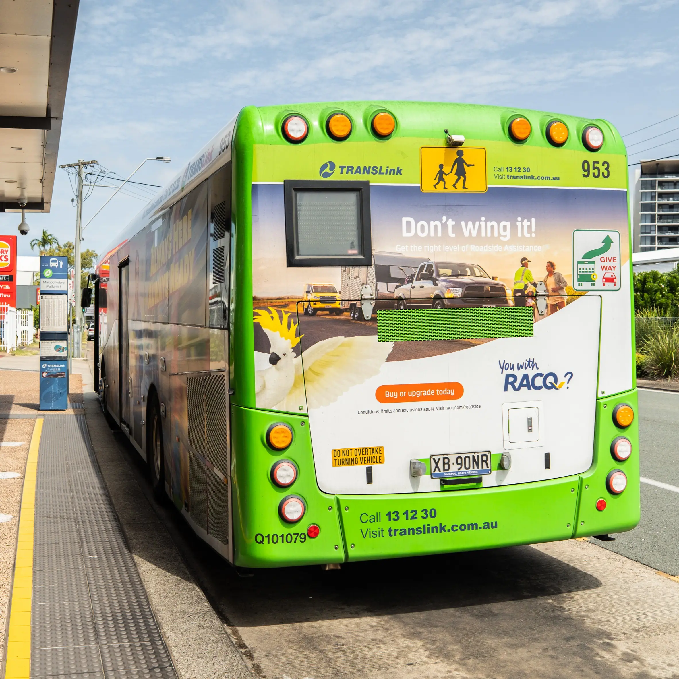 Full back panel advertisement for RACQ on the rear of a TransLink bus at a Sunshine Coast bus stop.