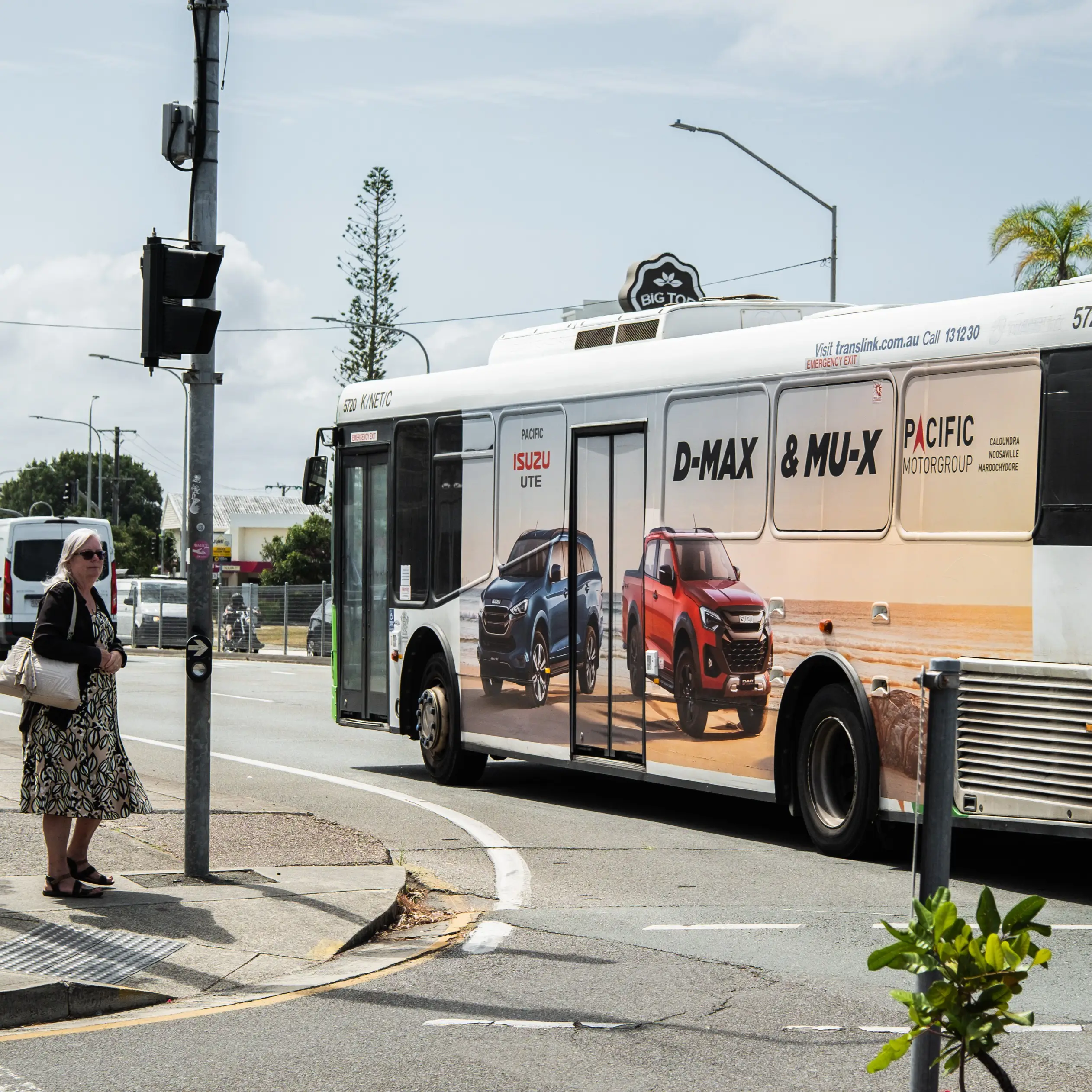 Megaside panel advertisement featuring Isuzu D-MAX and MU-X vehicles on the side of a TransLink bus turning through a busy intersection.