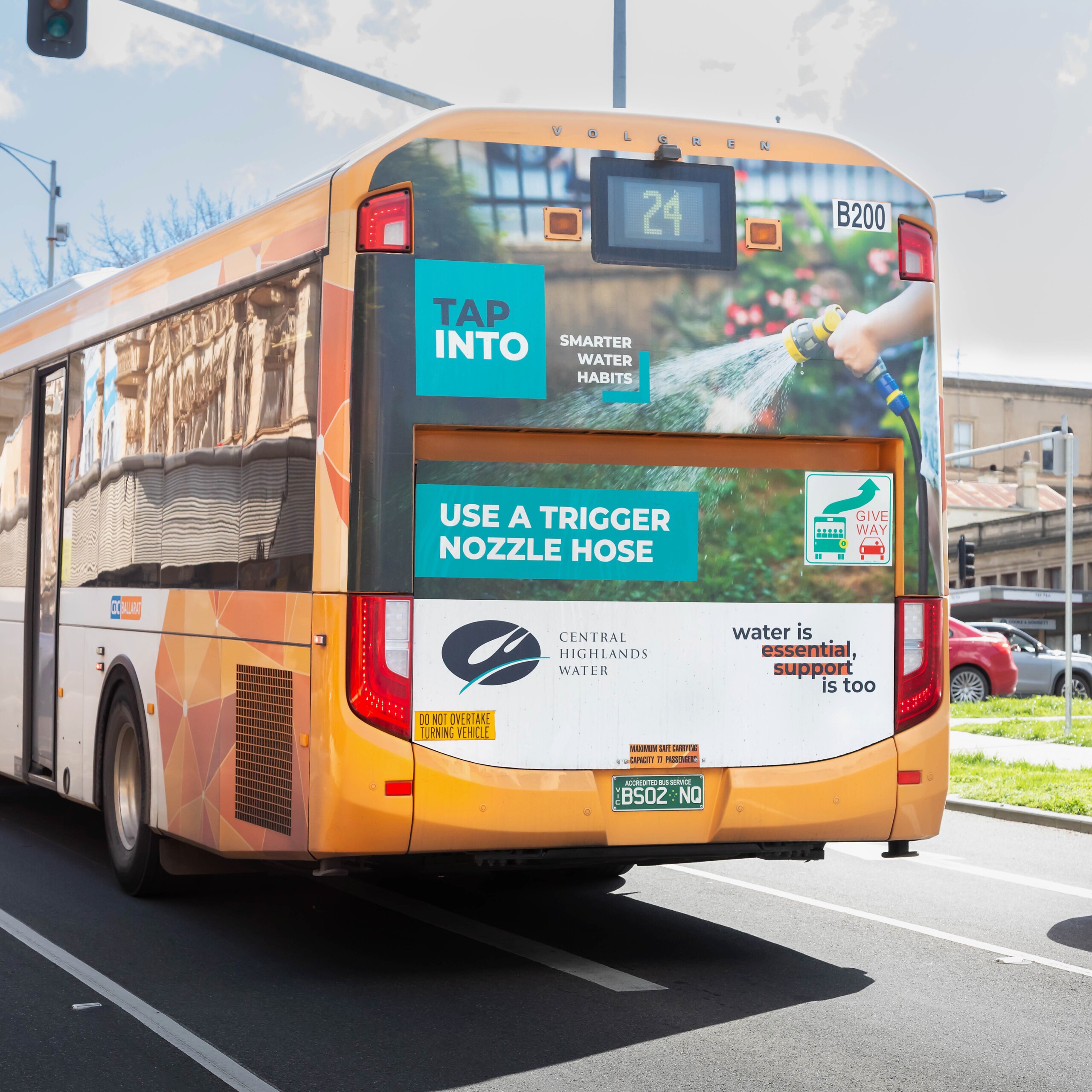 Back panel bus advertising promoting Central Highlands Water’s smart water habits campaign, featuring a trigger nozzle hose message on a bus driving through a suburban street.