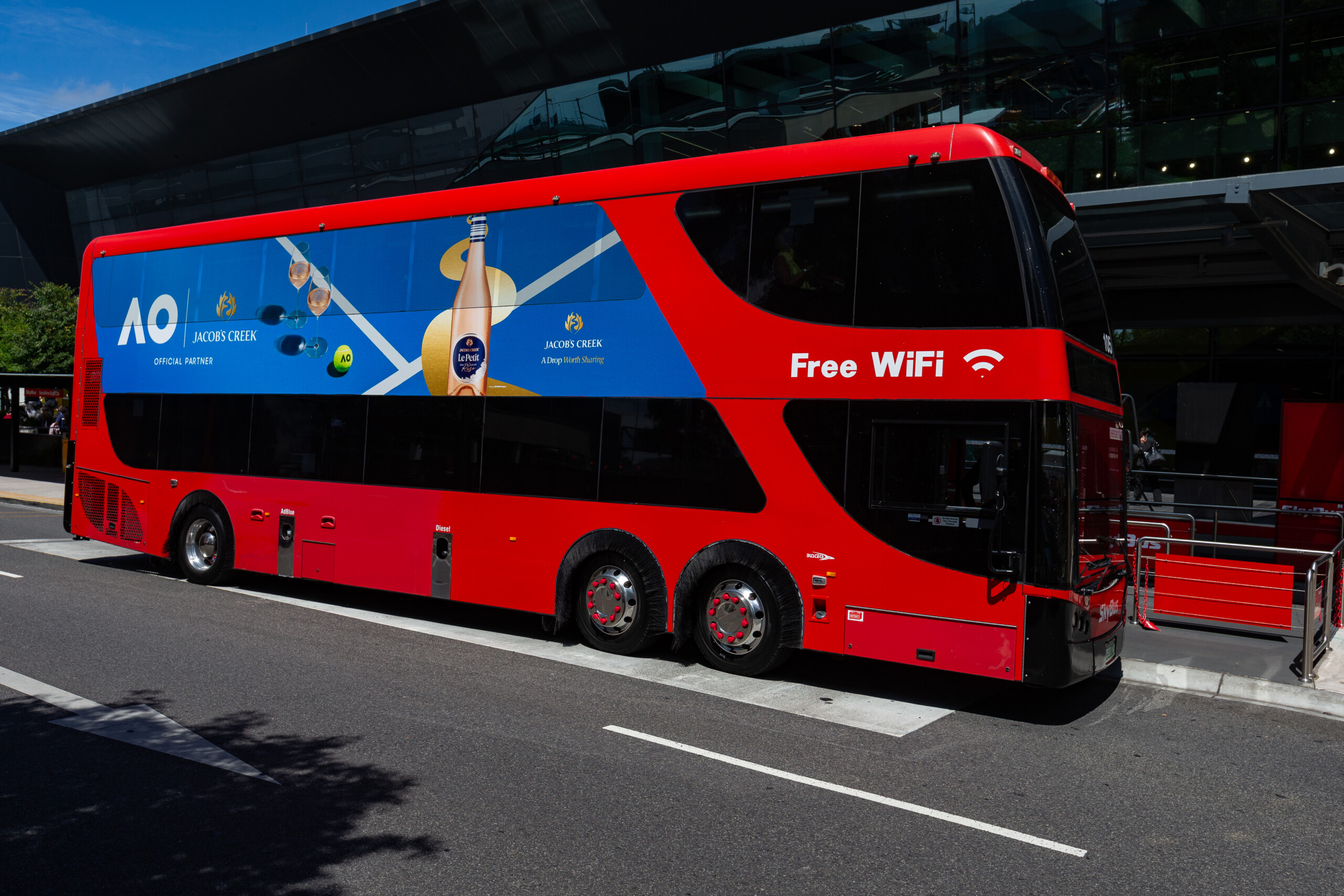 SkyBus double decker featuring premium SkyBus advertising parked at an airport terminal with large-format side creative.
